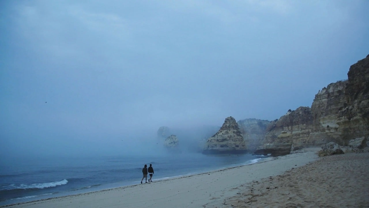 Two figures walking along a misty beach in the Algarve, from our 2019 Kickstarter film
